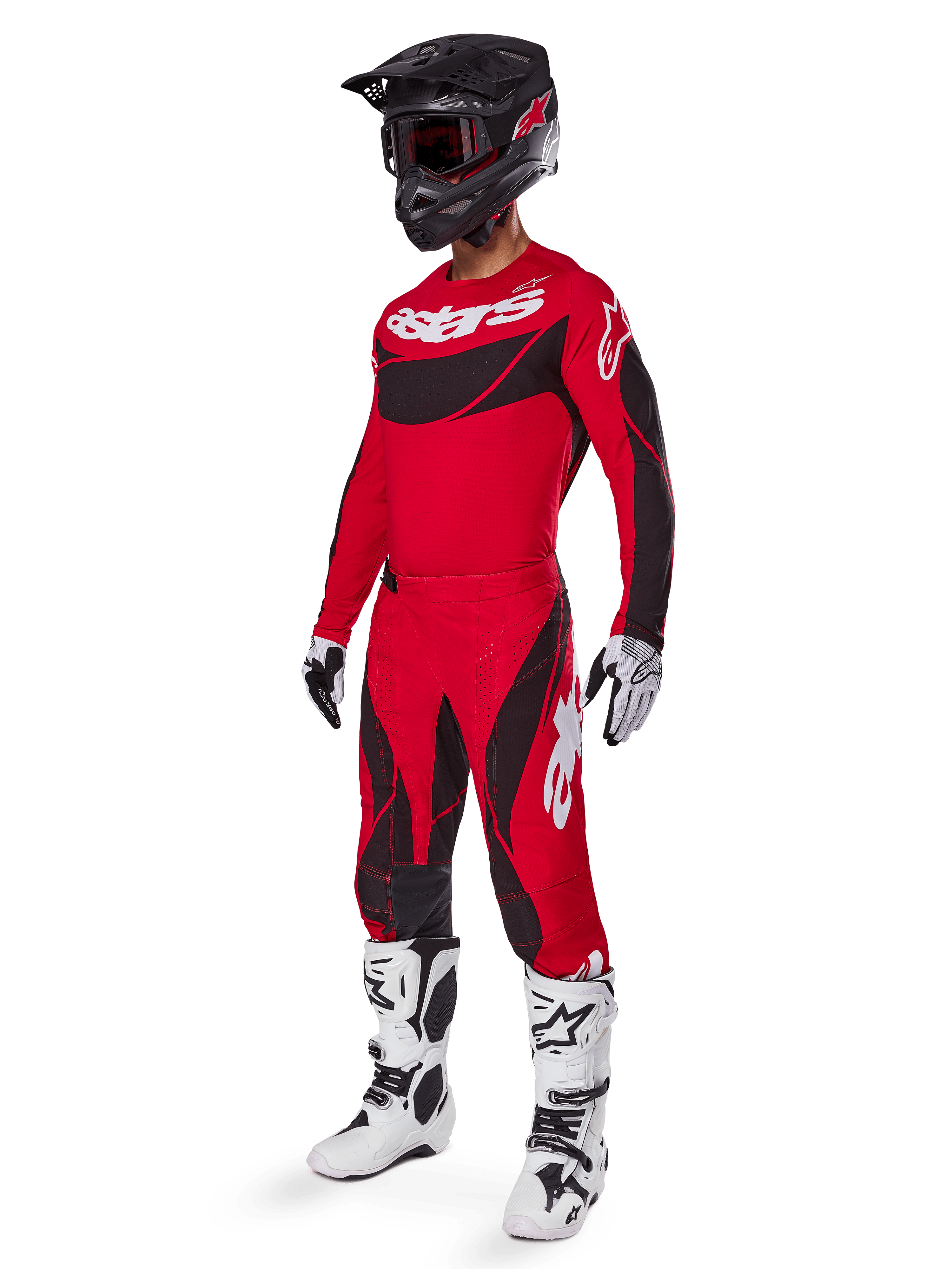 Vista de corpo inteiro de um piloto de motocross com o conjunto de equipamento Techstar Dreem 2025 em vermelho brilhante e preto, composto por camisola de performance com logótipo branco, calças ripstop elásticas a condizer, capacete preto com viseira vermelha, luvas brancas e pretas e botas Tech brancas, fato de corrida especializado para competição todo-o-terreno.