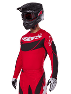 Alpinestars 2025 Techstar Dreem Gear Set, camisola e calças de motocross vermelhas com detalhes em preto e branco, usado com capacete e óculos pretos, luvas brancas e pretas, com a marca 'astars' em destaque, concebido para corridas de alto desempenho em todo-o-terreno