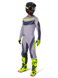 Conjunto de equipamento Alpinestars Techstar Dreem 2025, piloto de motocross com equipamento completo de corrida, camisola e calças cinzentas com padrões cinzento-escuro e pormenores em amarelo-verde néon, capacete preto a condizer, luvas e botas amarelo-verde néon, equipamento de performance para todo-o-terreno