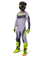 Conjunto de equipamento Alpinestars Techstar Dreem 2025, piloto de motocross com equipamento completo de corrida, camisola e calças cinzentas com padrões cinzento-escuro e pormenores em amarelo-verde néon, capacete preto a condizer, luvas e botas amarelo-verde néon, equipamento de performance para todo-o-terreno