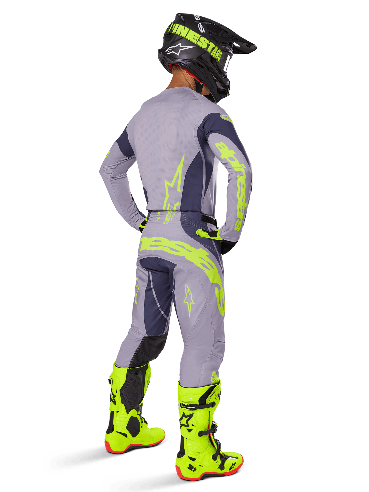Piloto de motocross visto de costas com o conjunto Alpinestars 2025 Techstar Dreem, cinzento e cinzento escuro com marca em amarelo fluorescente, camisola e calças a condizer, capacete preto com detalhes amarelos e botas amarelo fluorescente vibrante, equipamento de corrida profissional coordenado