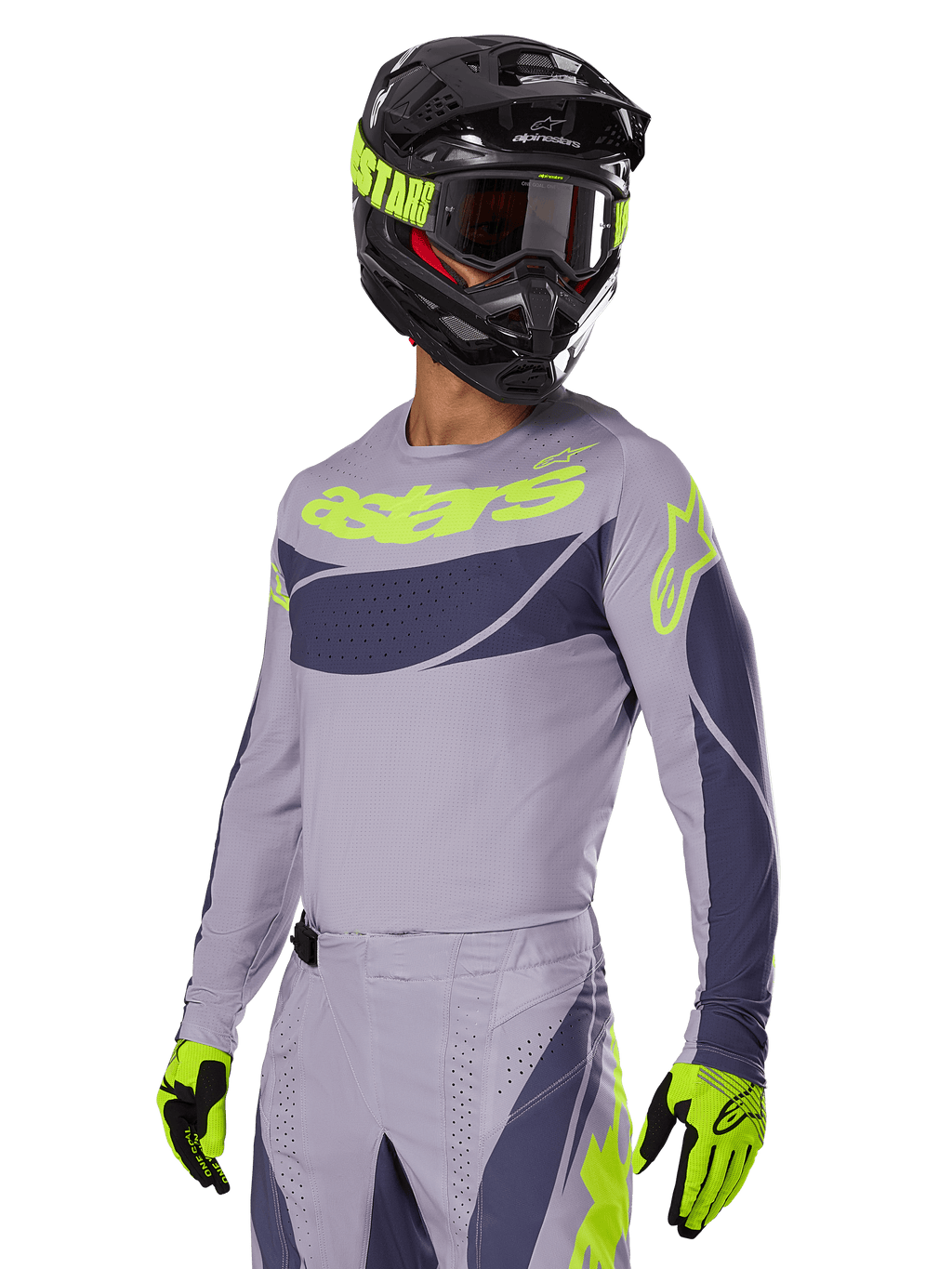 Piloto de motocross com a Camisola Alpinestars 2025 Techstar Dreem, cinzenta e cinzento escuro com logótipos verde lima, calças a condizer, capacete preto com pormenores verde lima, luvas verde lima e pretas, equipamento coordenado para corridas todo-o-terreno
