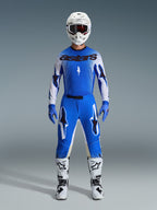 Motocross rider wearing the Alpinestars 2026 Supertech Scenz Gear Set in Ucla Blue and White, featuring a lightweight blue and white jersey with black branding, matching blue pants, white racing helmet, and white motocross boots, pro-level performance gear for off-road racing.