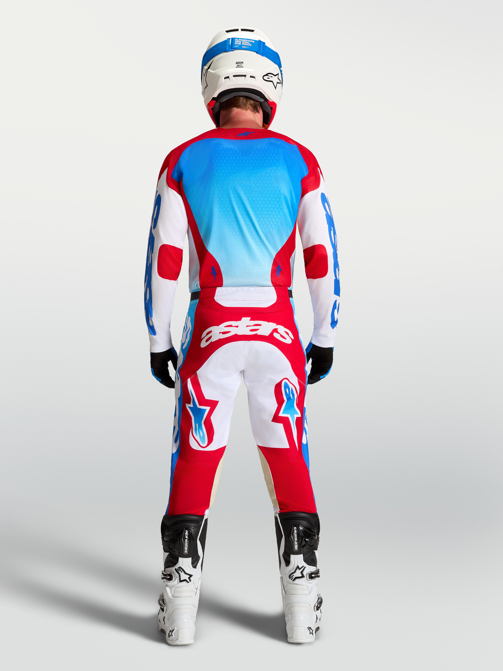 Alpinestars calças Racer Hunt e Gear Set, equipamento de motocross vermelho, branco e azul, vista traseira no modelo.