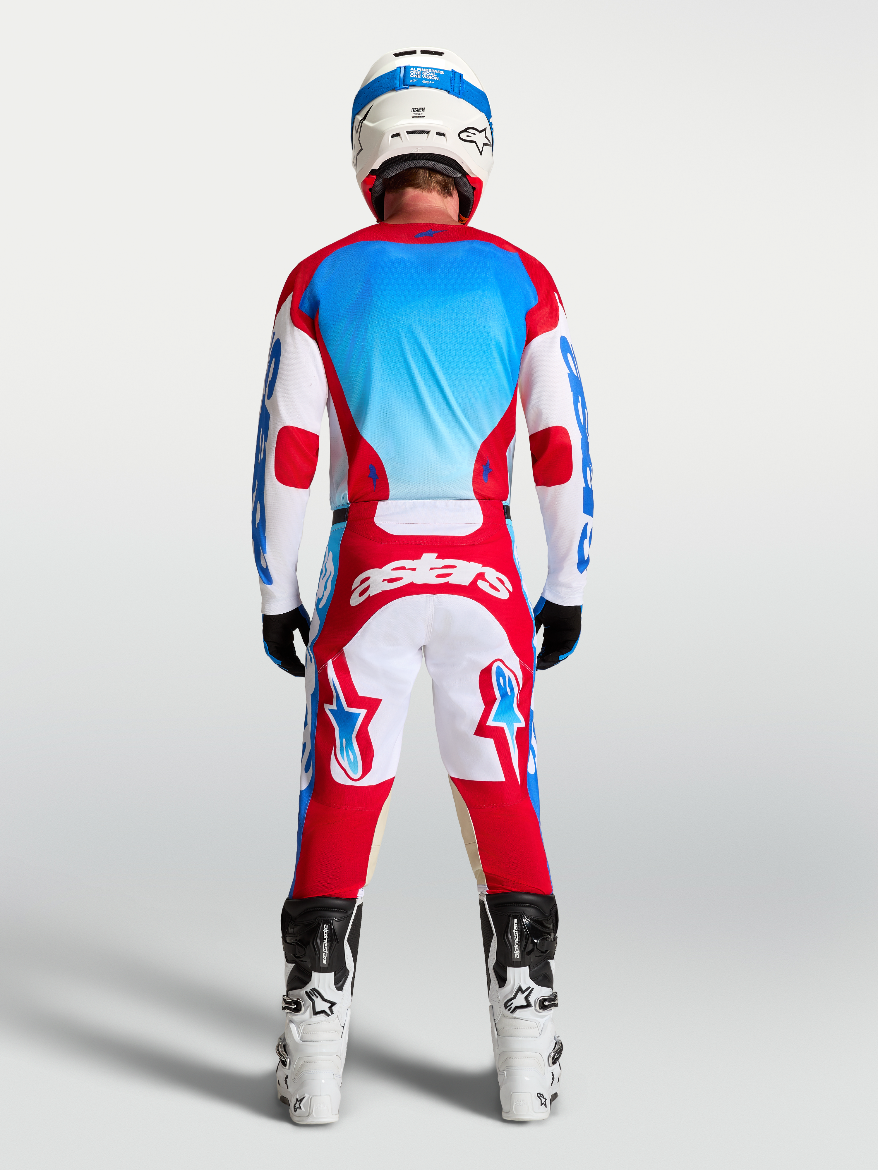 Alpinestars calças Racer Hunt e Gear Set, equipamento de motocross vermelho, branco e azul, vista traseira no modelo.