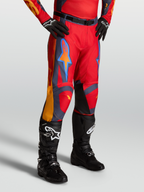 Alpinestars Calças Racer Hunt, calças de motocross para homem, vermelhas com detalhes cinzentos e coral, design ergonómico com botas pretas.