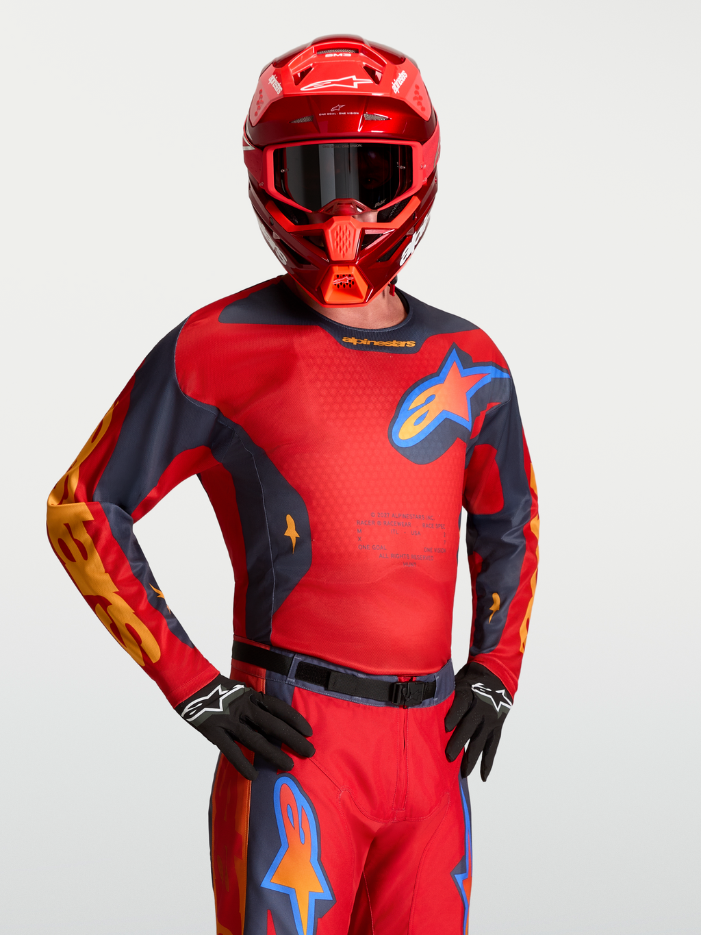Alpinestars camisola Racer Hunt, camisola de motocross vermelha e cinzenta, com painéis de malha, usada com capacete a condizer.