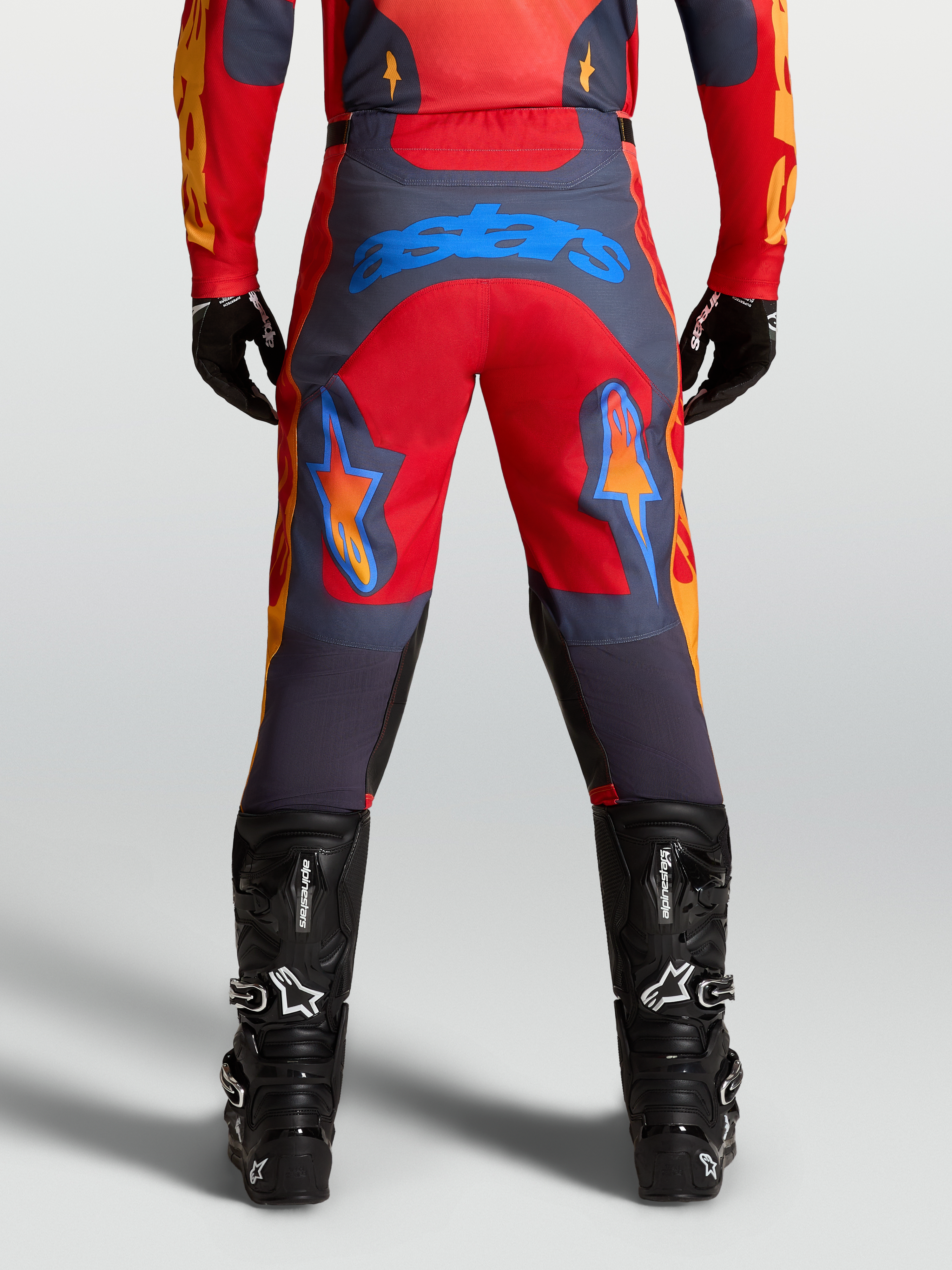 Alpinestars Calças Racer Hunt, calças de motocross para homem, vermelho e cinzento, vista traseira com logótipo azul no assento e pernas pré-curvadas