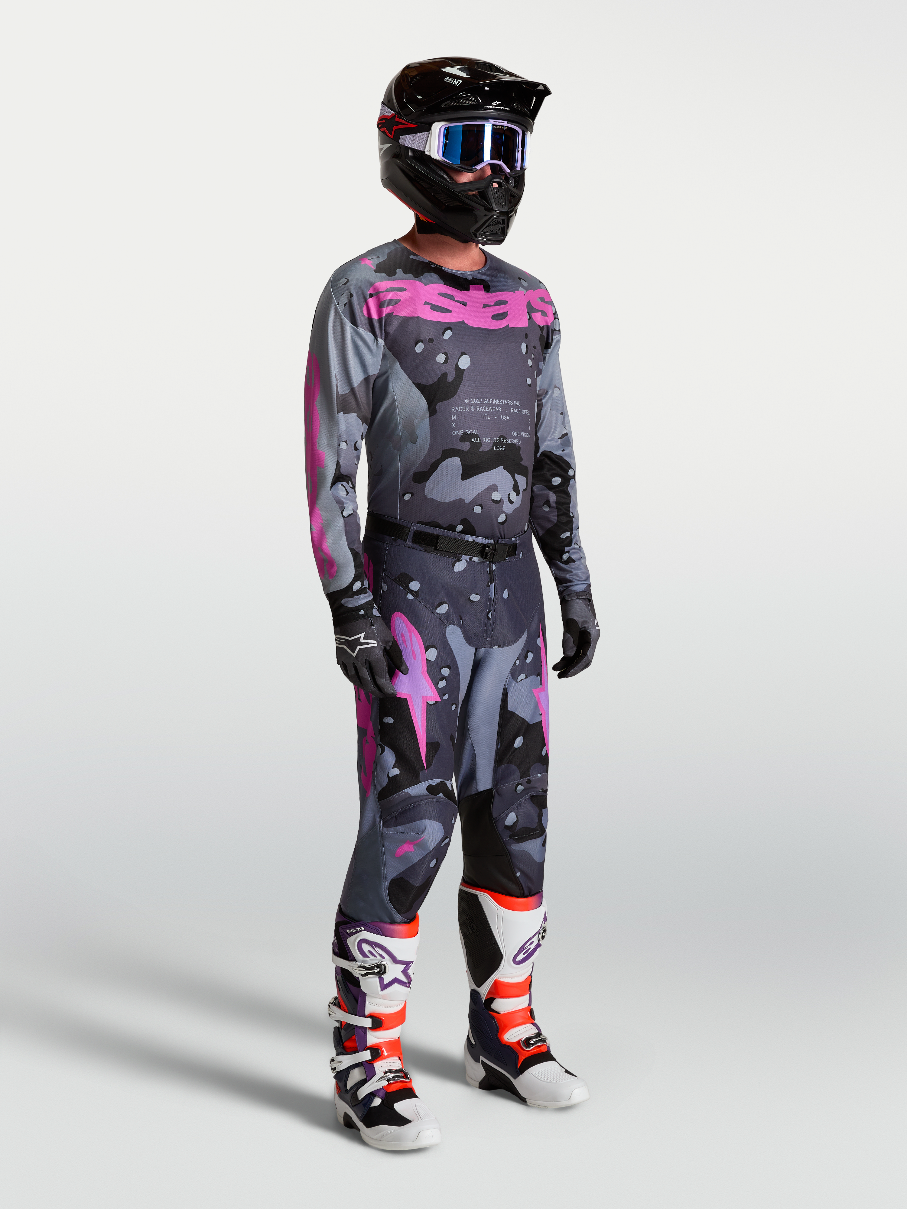 Alpinestars Racer Lone, conjunto de camisola e calças de motocross para homem, cinzento e roxo camuflado com botas e capacete.