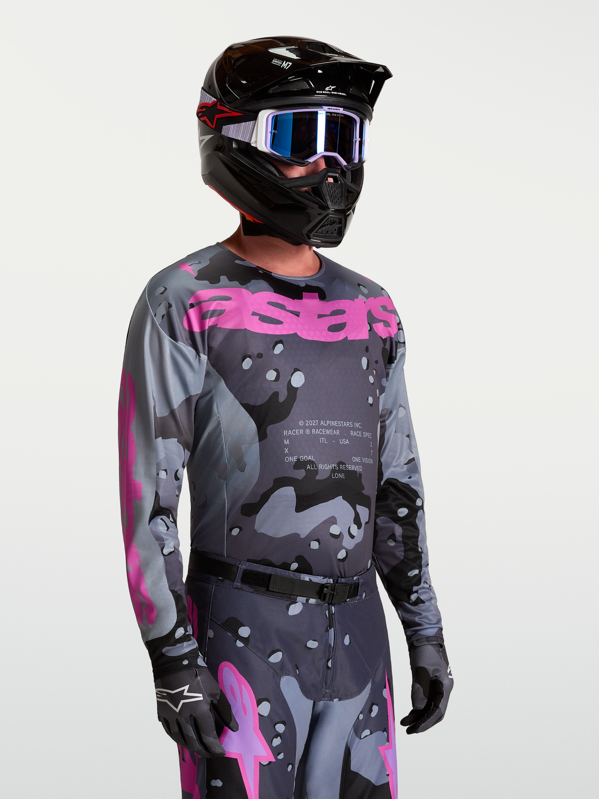 Alpinestars Camisola Racer Lone, camisola de motocross para homem, cinzento camuflado e roxo, vista frontal em modelo com equipamento completo de motocross.