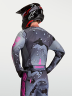 Alpinestars Camisola Racer Lone, camisola de motocross unissexo, padrão camuflagem cinzenta e roxa, vista traseira no modelo, tecido técnico polifabric respirável.