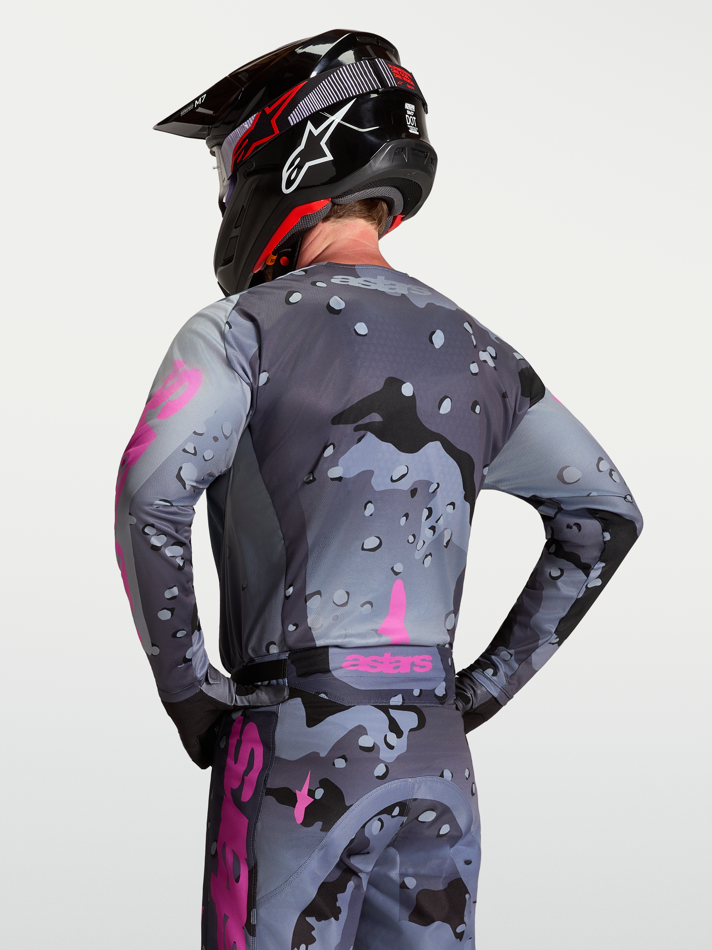 Alpinestars Camisola Racer Lone, camisola de motocross unissexo, padrão camuflagem cinzenta e roxa, vista traseira no modelo, tecido técnico polifabric respirável.