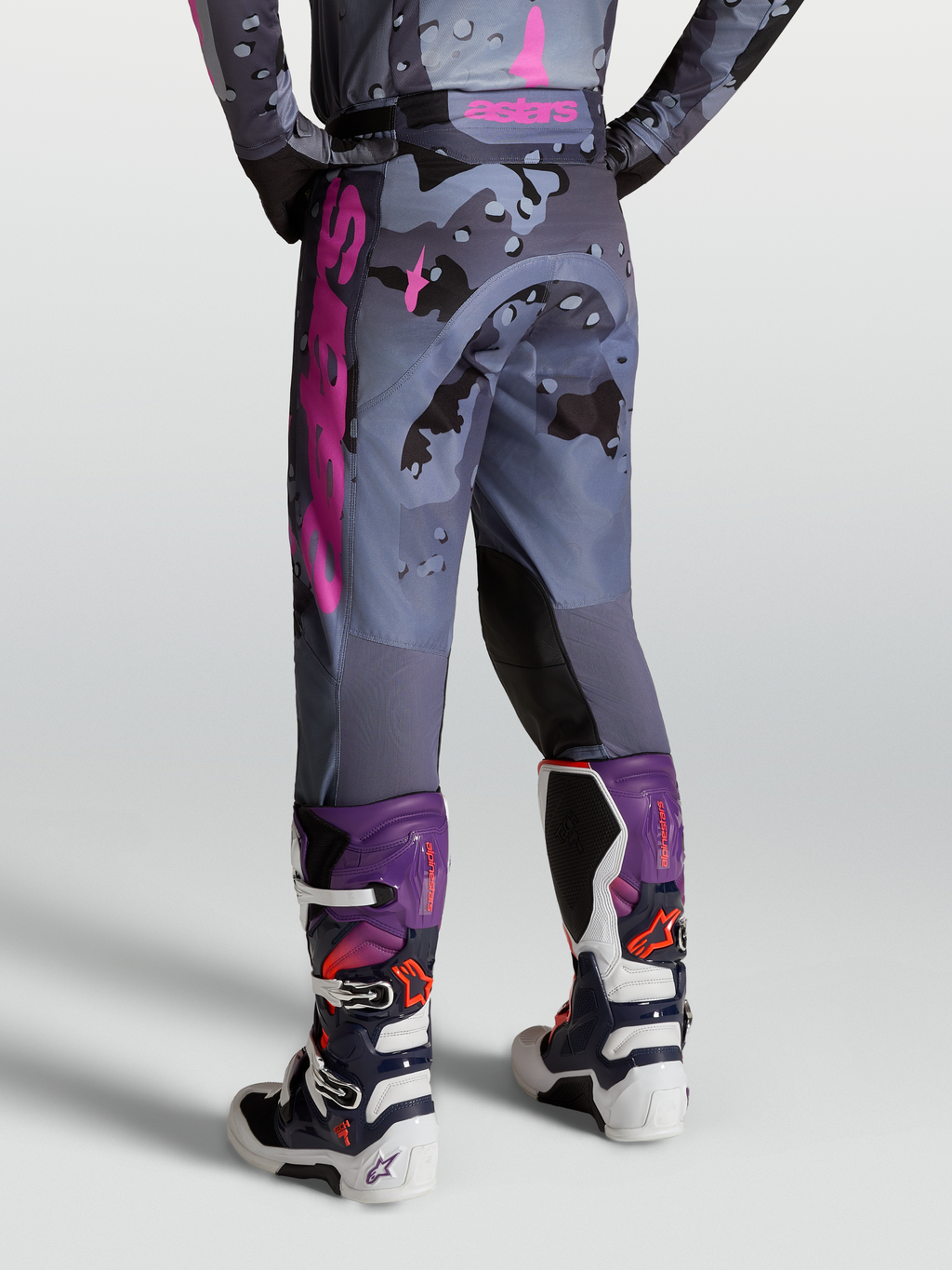Alpinestars Calças Racer Lone, calças de motocross para homem em padrão camo cinzento e roxo, vista traseira com botas Tech 7.
