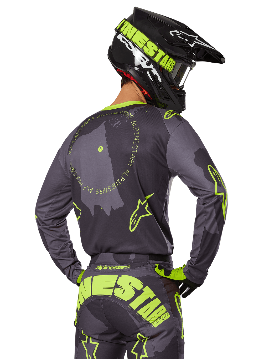 Piloto de motocross visto de costas a usar o Conjunto de Equipamento Racer Hollow 2025, camisola cinzenta com texto circular amarelo fluorescente e logótipos de estrela, calças cinzentas e amarelas a condizer com marca proeminente no assento, capacete preto e verde-lima, conjunto coordenado para corridas fora de estrada