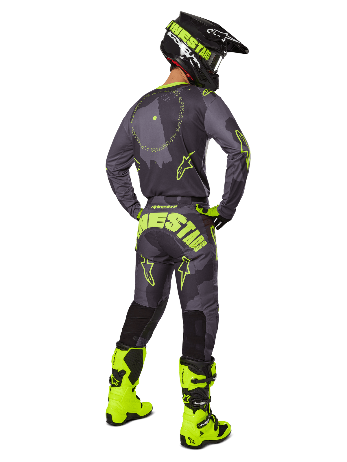 Vista traseira de um piloto de motocross a usar o conjunto de equipamento Racer Hollow 2025 em Dark Camo Yellow Fluo, com uma camisola camuflada cinzenta com detalhes em amarelo néon, calças de motocross a condizer com marca de destaque no assento, botas em amarelo néon brilhante e um capacete preto com óculos amarelos.