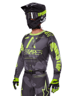 Conjunto de Equipamento Alpinestars 2025 Racer Hollow, camisola e calças de motocross em cinzento e amarelo néon, usado com capacete, óculos e luvas pretas a condizer, com a marca Alpinestars em amarelo fluorescente e gráficos de estrelas sobre uma base cinzenta padronizada, visual de corrida off-road profissional coordenado