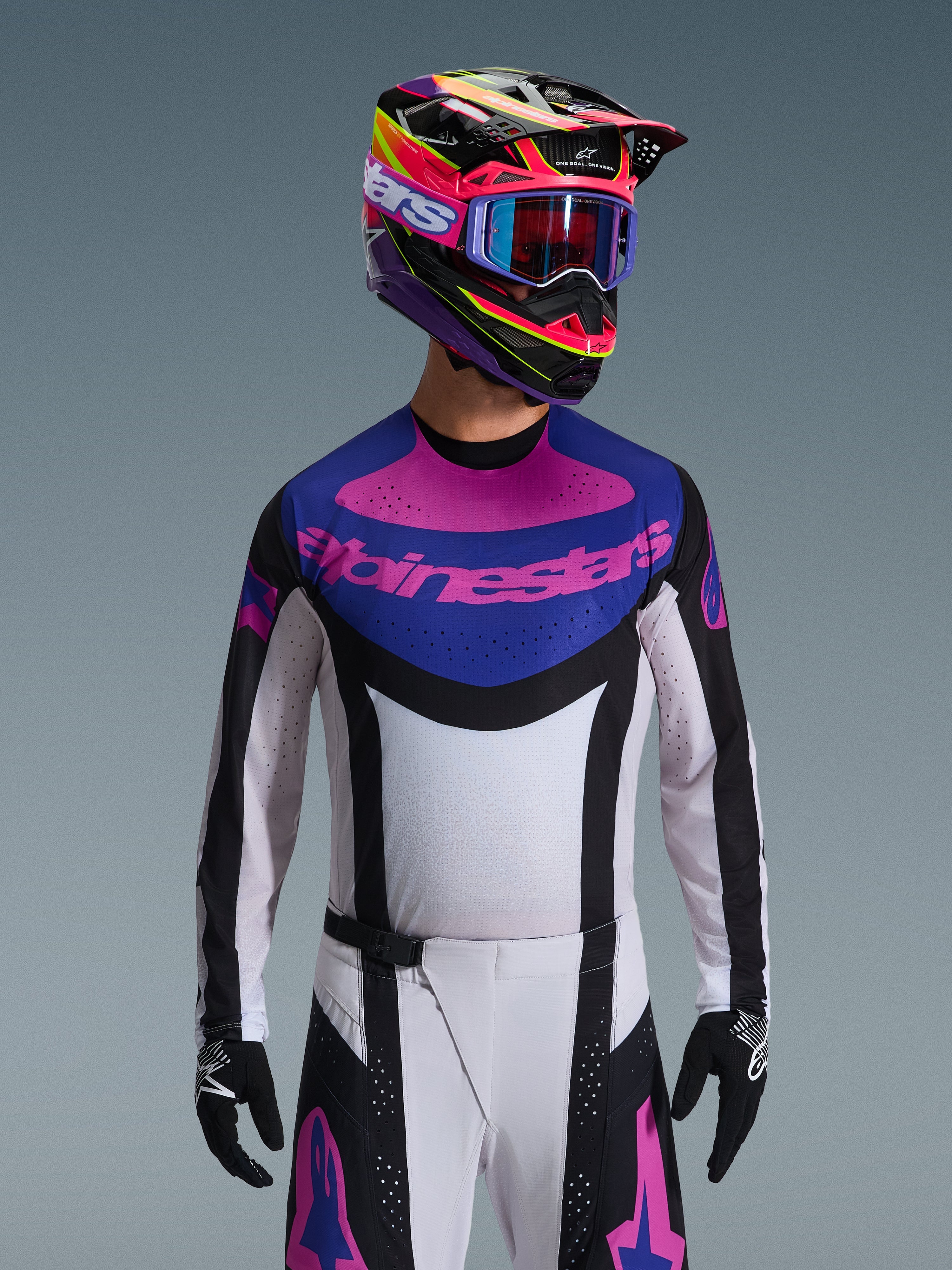 Alpinestars 2026 Techstar Knif Jersey, camisola de motocross, preta, cinzento claro e roxa, logótipo Alpinestars cor-de-rosa no peito, usada com capacete colorido e calças de motocross condizentes, ajuste atlético de corrida com perfurações a laser para ventilação