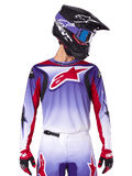 Alpinestars 2025 Fluid Wurx Jersey, camisola de motocross, degradê de roxo para branco, logótipo de estrela e detalhes em vermelho, corte atlético, usada com calças a condizer, capacete preto e luvas vermelhas