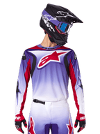 Alpinestars 2025 Fluid Wurx Jersey, camisola de motocross, degradê de roxo para branco, logótipo de estrela e detalhes em vermelho, corte atlético, usada com calças a condizer, capacete preto e luvas vermelhas