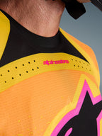 Alpinestars 2026 Techstar Nomur Jersey, camisola de motocross, laranja, amarelo e rosa, pormenor em grande plano do peito e da gola, com ventilação cortada a laser, logótipo cor-de-rosa e tecido de malha respirável