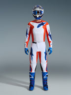 Conjunto de equipamento Alpinestars 2026 Fluid Grid, piloto de motocross com equipamento completo, camisola e calças brancas com detalhes em laranja e azul UCLA, capacete azul e branco a condizer com óculos azuis, luvas e botas de motocross azuis, fato de corrida off-road coordenado