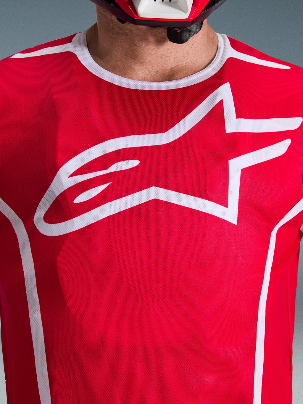 Close-up of Alpinestars 2026 Fluid Apex Jersey in Red and White, featuring a large white Astars logo on the chest, breathable polyfabric mesh construction, and white collar trim, motocross racing apparel.