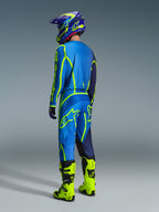 Piloto de motocross visto de costas a usar a Camisola Alpinestars 2026 Fluid Apex em Azul Amarelo Fluo, calças a condizer em azul e amarelo fluorescente, botas amarelo néon e capacete coordenado, equipamento profissional de corrida para todo-o-terreno