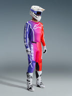 Piloto de motocross com equipamento de corrida completo, Camisola e Calças Fluid Apex 2026 com um gradiente vibrante de roxo, rosa e laranja, capacete branco com óculos azuis, botas brancas e pretas, e luvas brancas, conjunto coordenado para motocross todo-o-terreno
