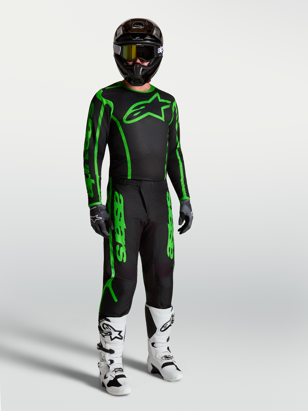 Alpinestars Camisola Fluid Apex V2, para motocross, homem, preta e verde fluo, em modelo com calças e botas.