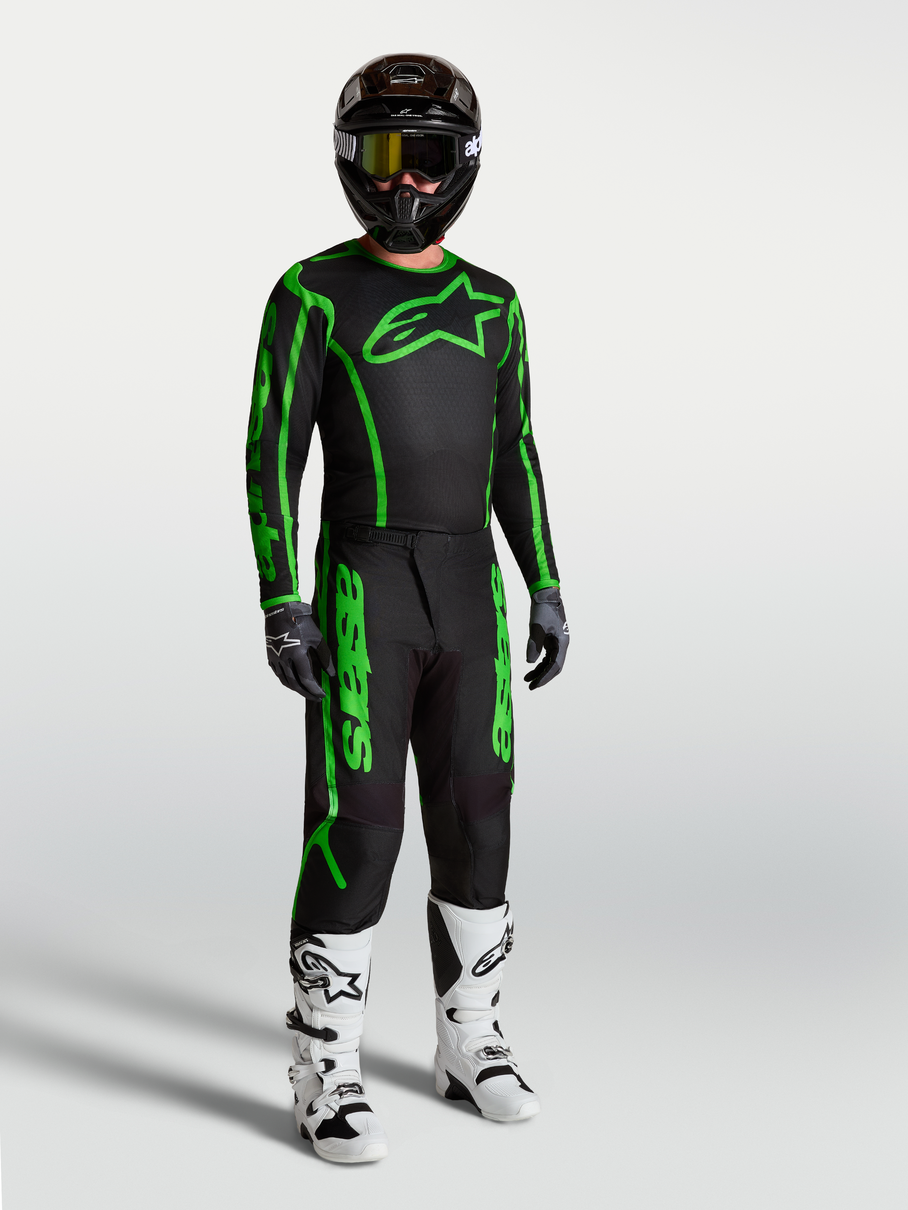 Alpinestars Camisola Fluid Apex V2, para motocross, homem, preta e verde fluo, em modelo com calças e botas.