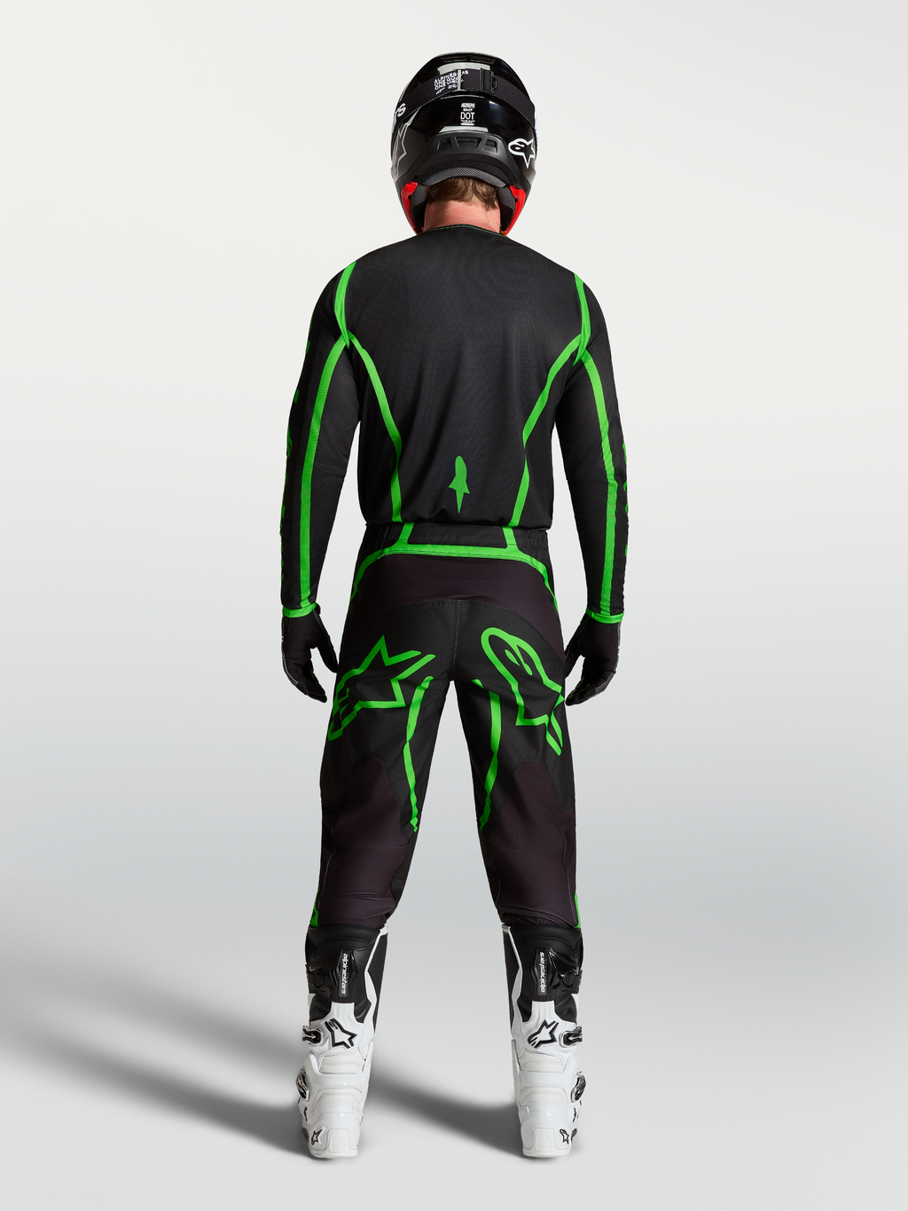Alpinestars camisola Fluid Apex V2 para homem, em preto e verde fluorescente, vista traseira no piloto com botas brancas.
