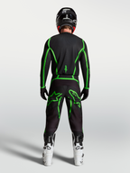 Alpinestars camisola Fluid Apex V2 para homem, em preto e verde fluorescente, vista traseira no piloto com botas brancas.