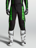 Calças Alpinestars Fluid Apex V2, calças de motocross para homem, verdes e pretas, com joelhos reforçados e botas brancas.