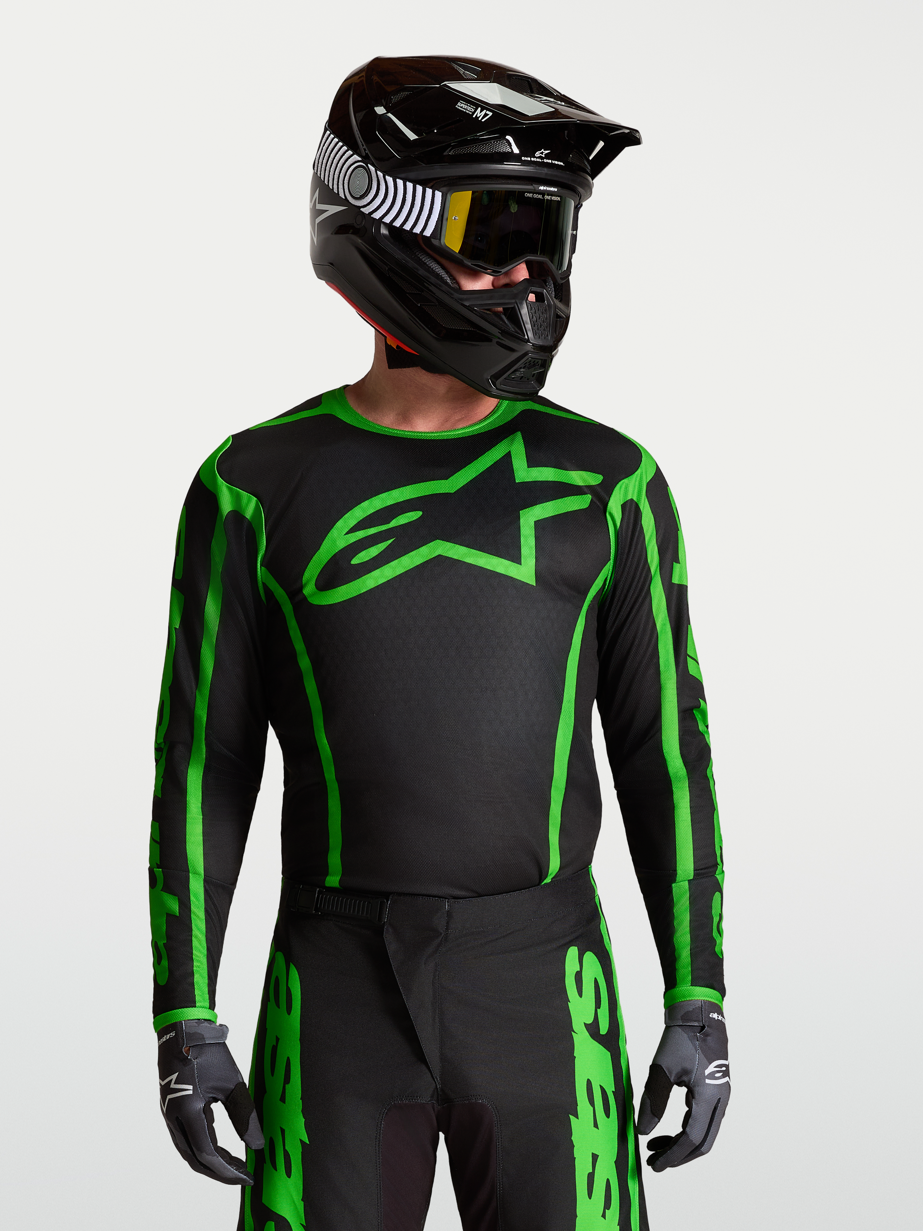 Alpinestars Camisola Fluid Apex V2, camisola de motocross para homem, preta e verde fluorescente, modelo equipado com capacete e luvas