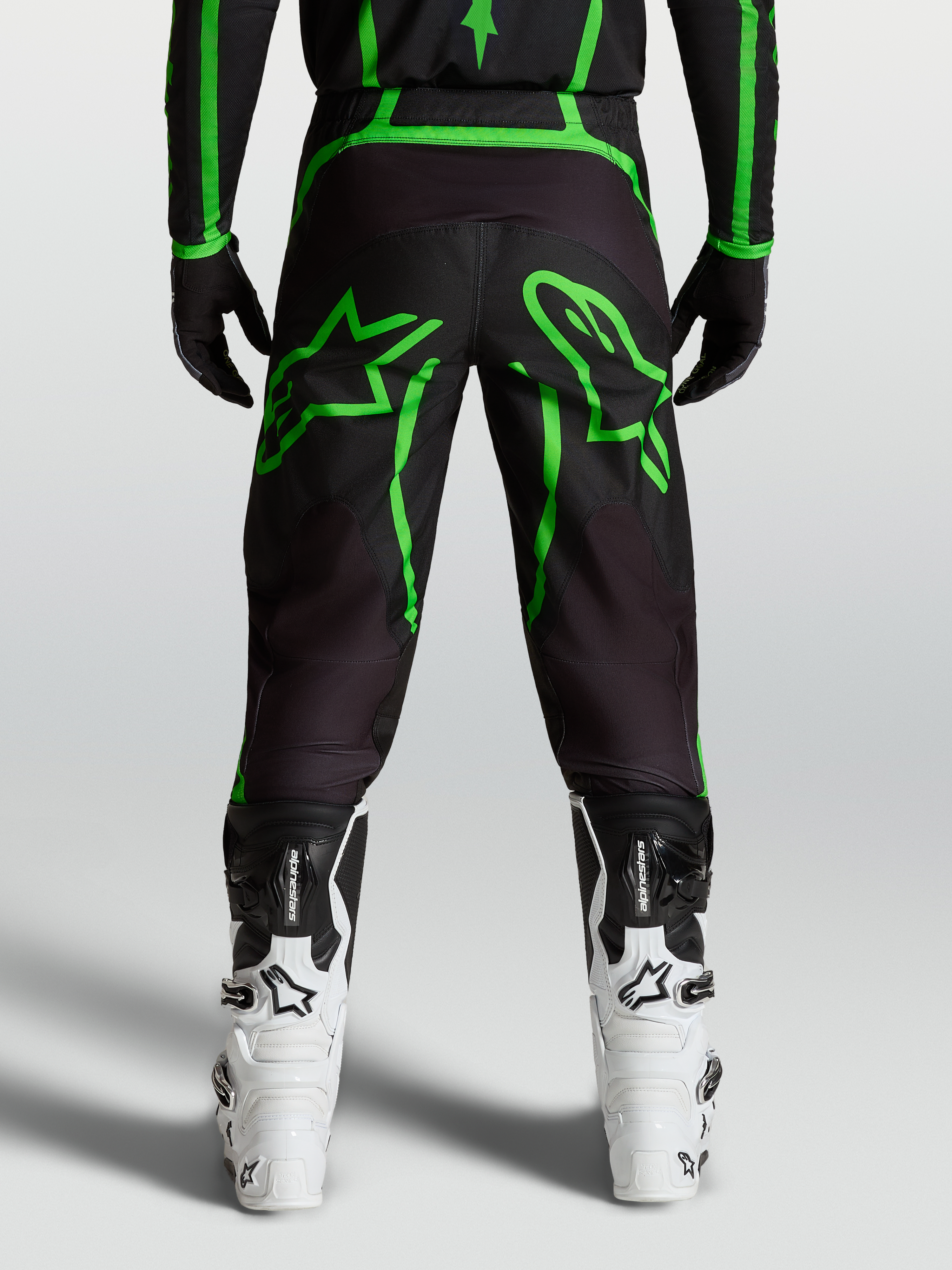 Alpinestars Calças Fluid Apex V2, calças de motocross para homem, pretas e verdes florescentes, com gráficos de estrelas, vista traseira no modelo