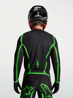 Camisola Alpinestars Fluid Apex V2 para motocross, preta e verde fluorescente, vista traseira com corte longo no modelo.