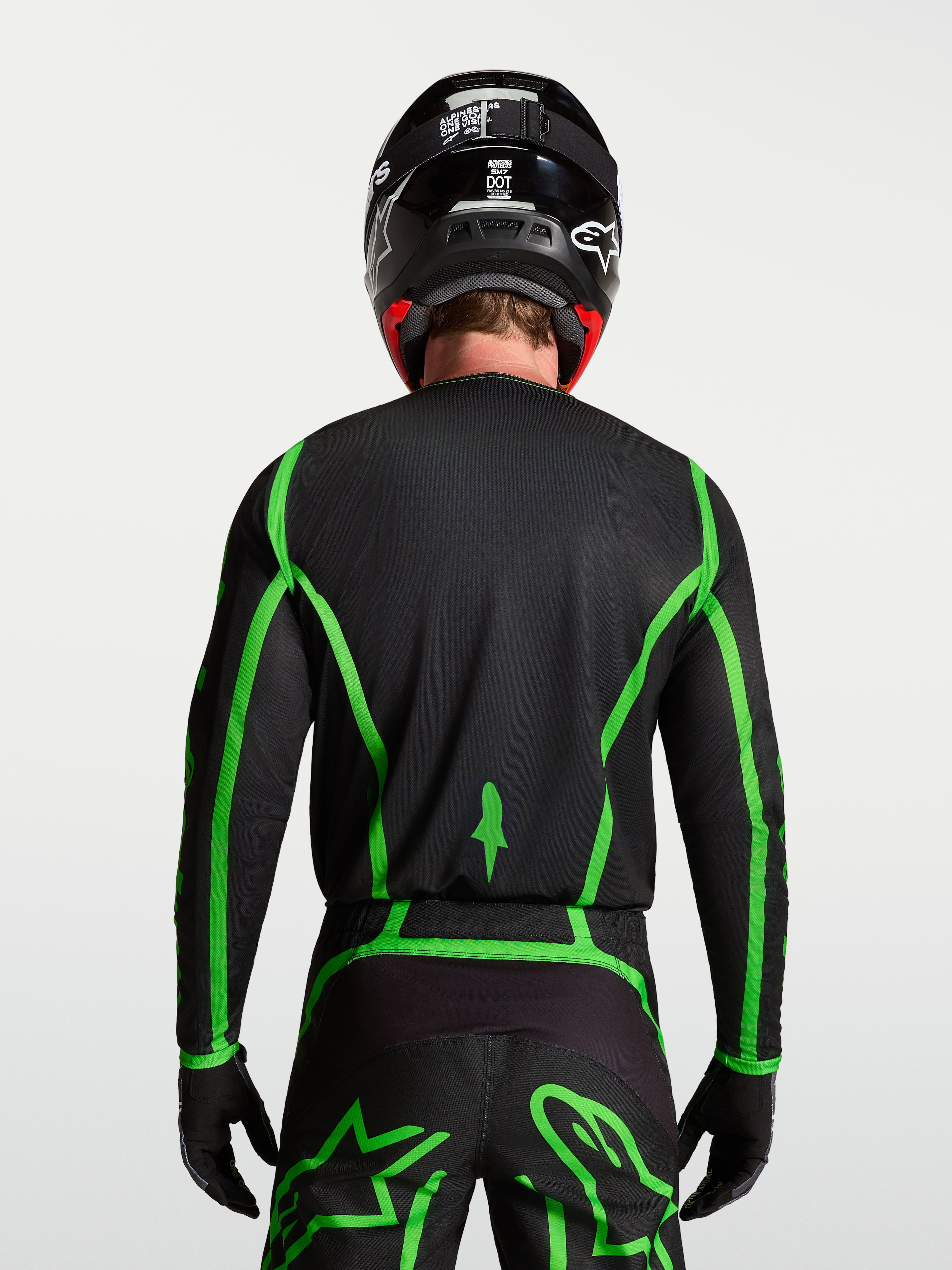 Camisola Alpinestars Fluid Apex V2 para motocross, preta e verde fluorescente, vista traseira com corte longo no modelo.