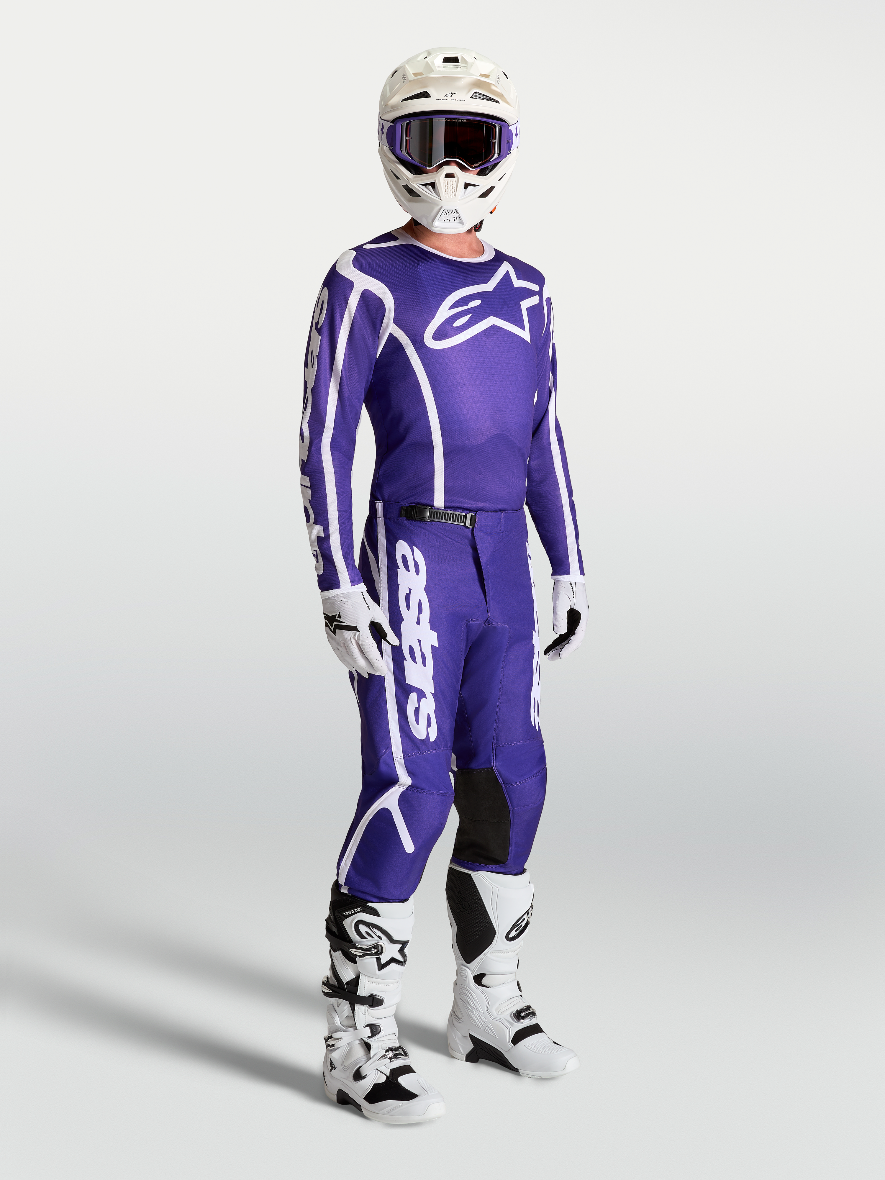 Camisola Alpinestars Fluid Apex V2 e calças de motocross, azul e branco, conjunto no modelo com botas e capacete, equipamento técnico para todo-o-terreno