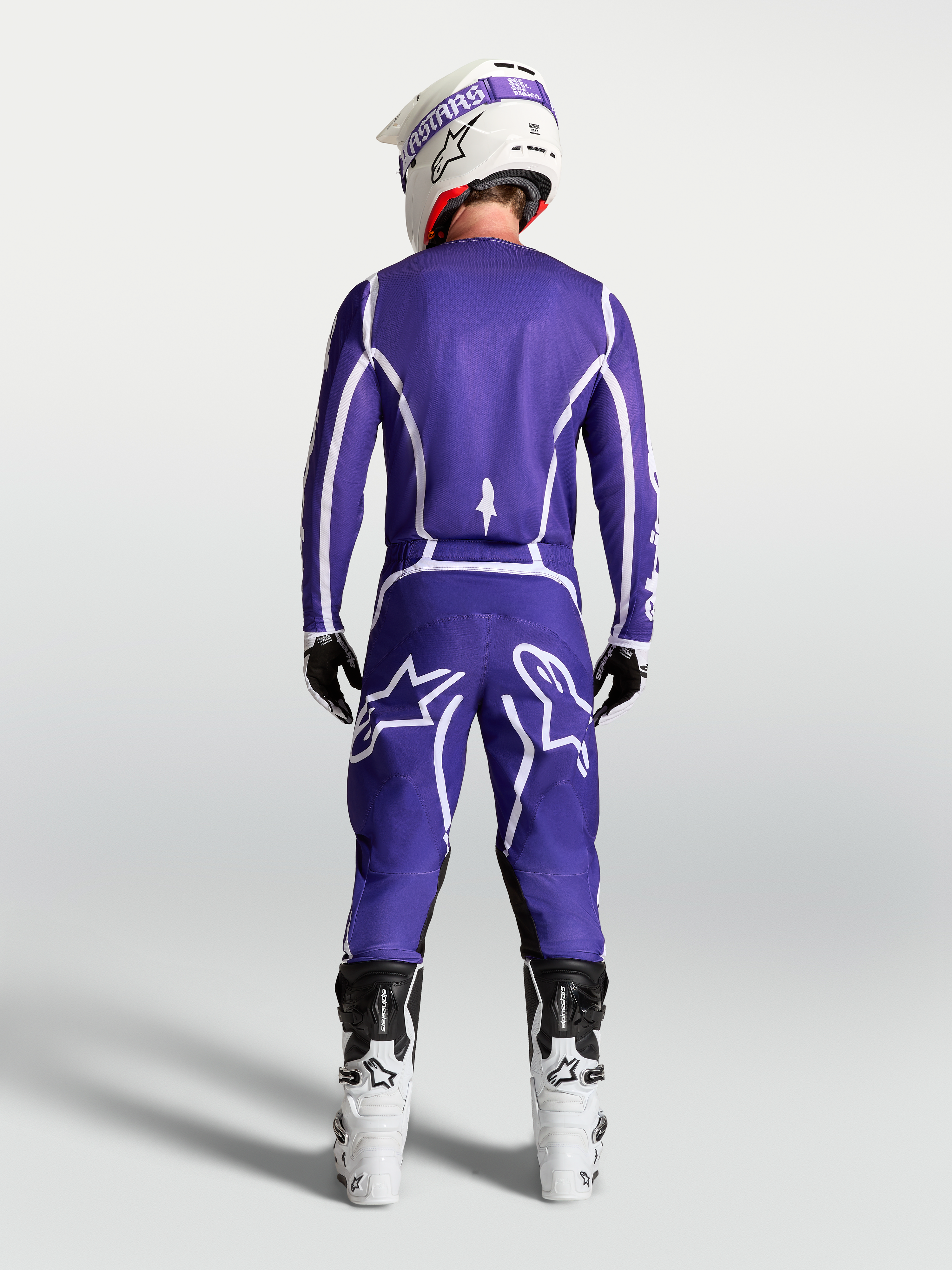 Camisola Alpinestars Fluid Apex V2, camisola de motocross azul escuro e branco, vista traseira com calças e botas brancas.