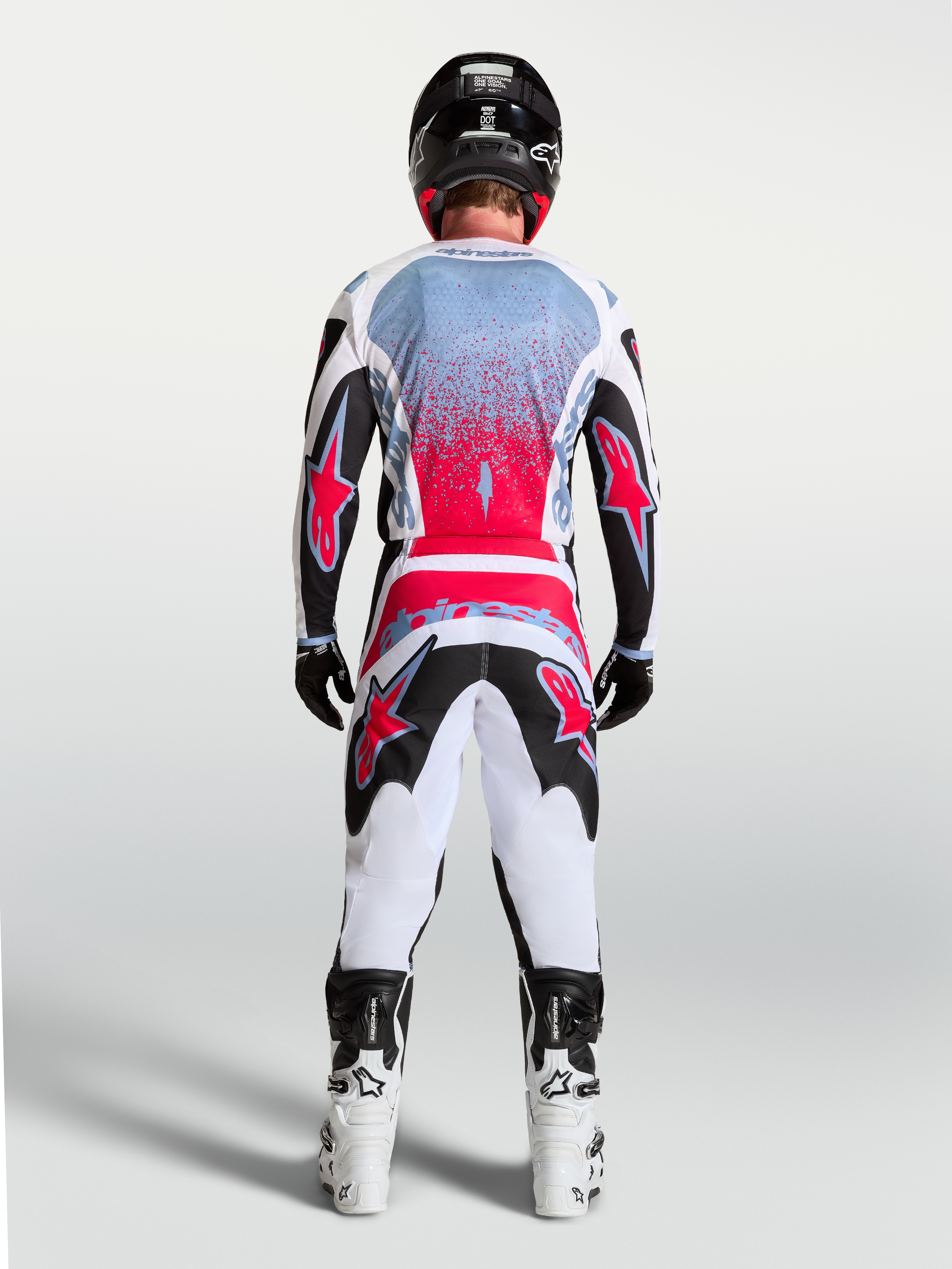 Alpinestars camisola Fluid Drag de motocross para homem, preta e vermelha fluo, vista traseira num piloto, design de performance para todo-o-terreno
