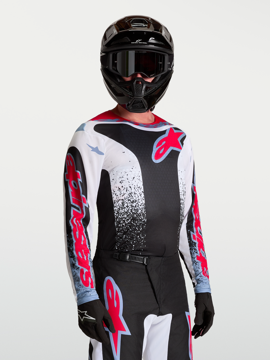 Alpinestars Camisola Fluid Drag, camisola de motocross para homem, preta, branca, vermelha e azul, tecido leve e respirável, modelo a usar equipamento completo de todo-o-terreno.