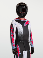 Alpinestars Camisola Fluid Drag, camisola de motocross para homem, preta, branca, vermelha e azul, tecido leve e respirável, modelo a usar equipamento completo de todo-o-terreno.