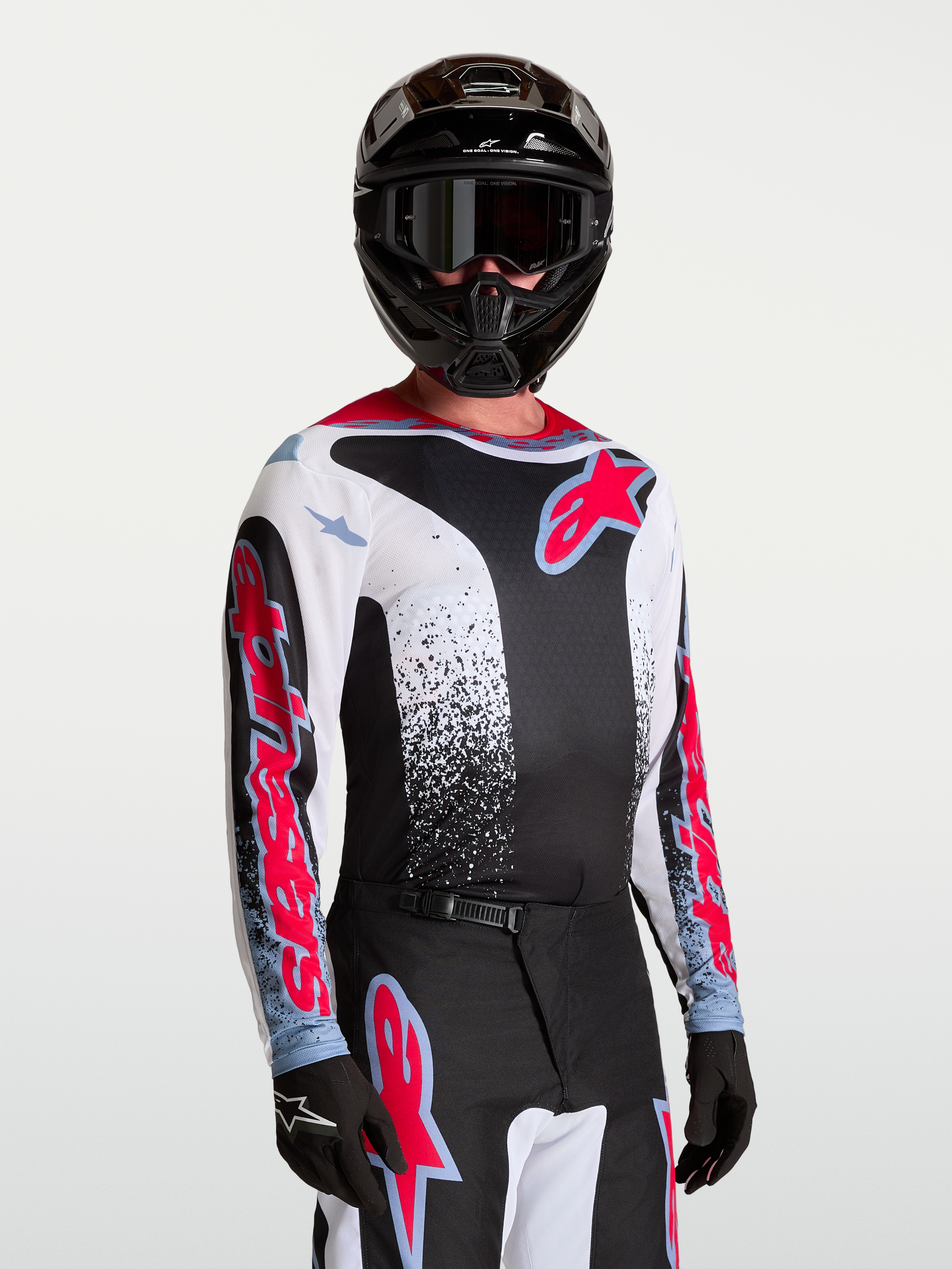 Alpinestars Camisola Fluid Drag, camisola de motocross para homem, preta, branca, vermelha e azul, tecido leve e respirável, modelo a usar equipamento completo de todo-o-terreno.