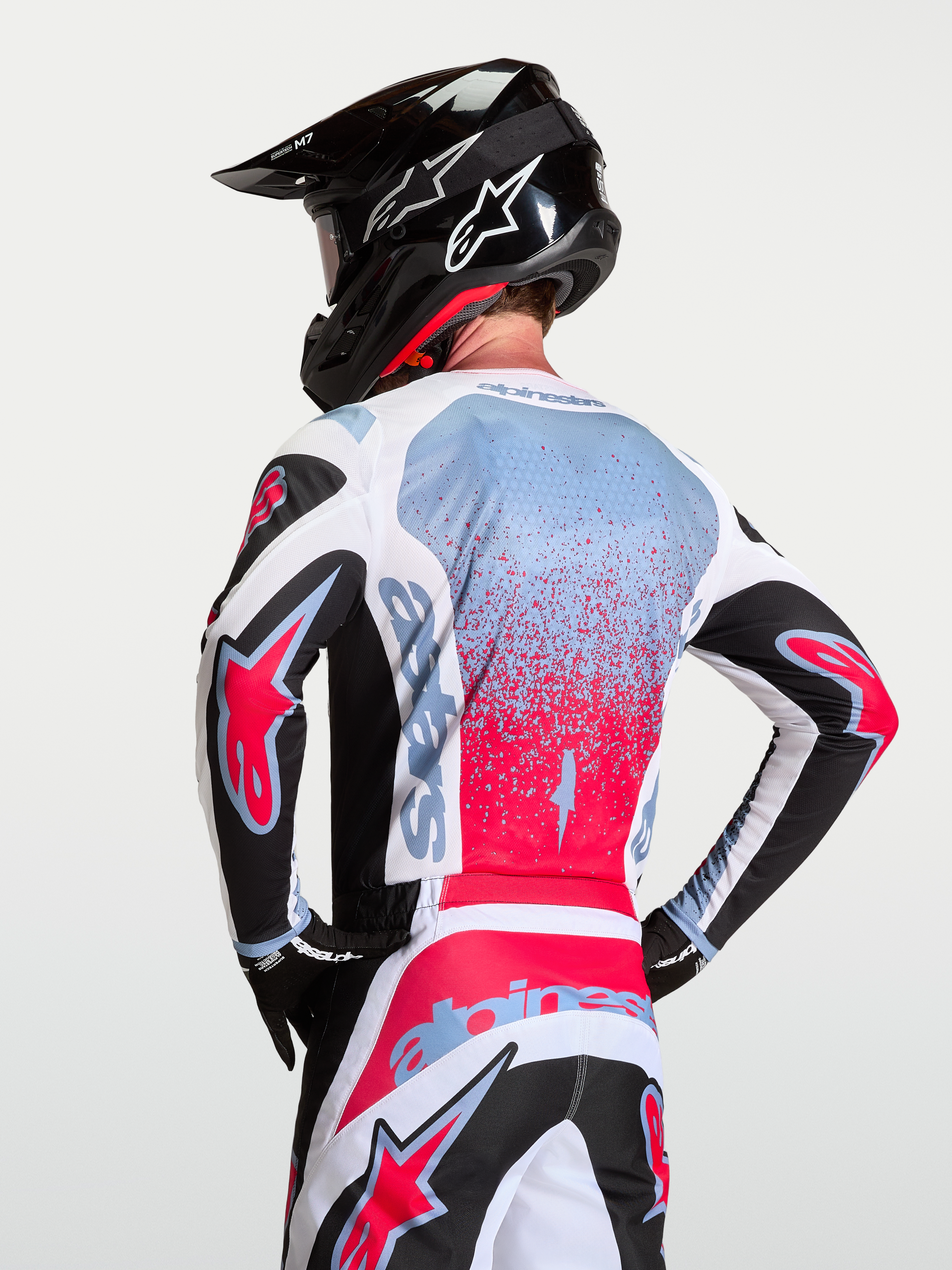 Alpinestars Camisola Fluid Drag, equipamento de motocross para homem em preto, branco e vermelho com detalhes azul claro, vista traseira e tecido respirável.
