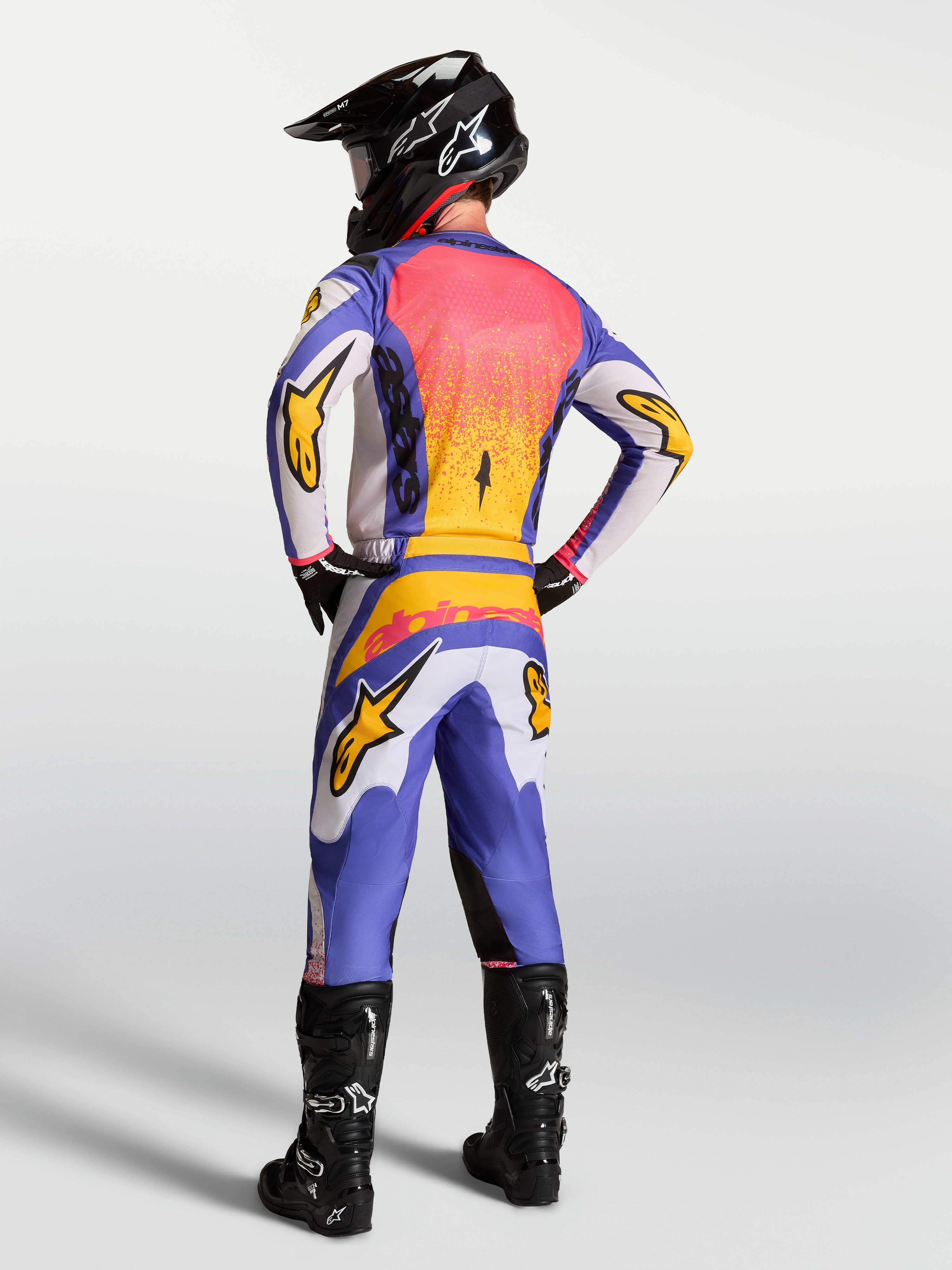 Alpinestars Fluid Drag Gear Set, conjunto de motocross para homem, azul e lilás claro com dourado, vista traseira no modelo.