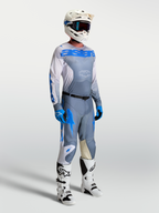 Alpinestars Camisola Racer Amber, equipamento de motocross para homem, cinzento e azul, no modelo com capacete e botas.