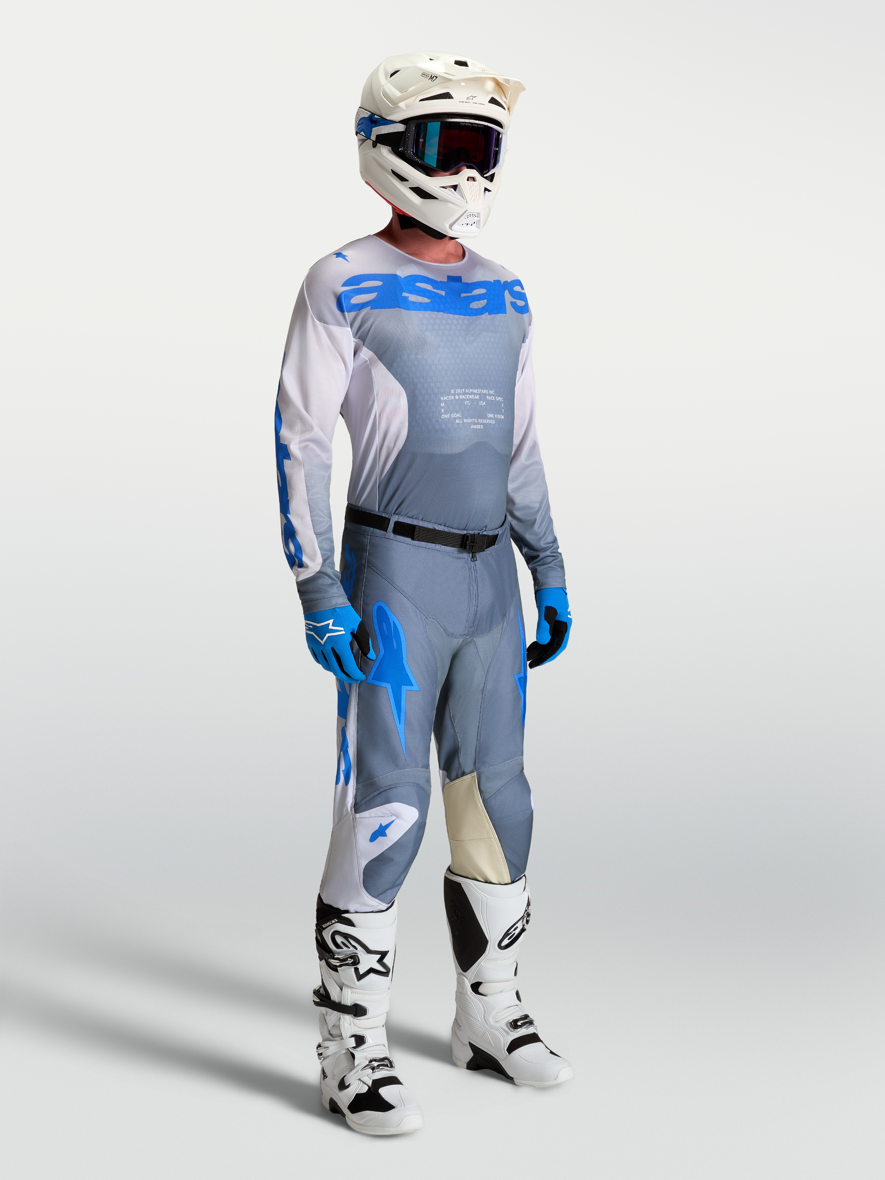 Alpinestars Camisola Racer Amber, equipamento de motocross para homem, cinzento e azul, no modelo com capacete e botas.