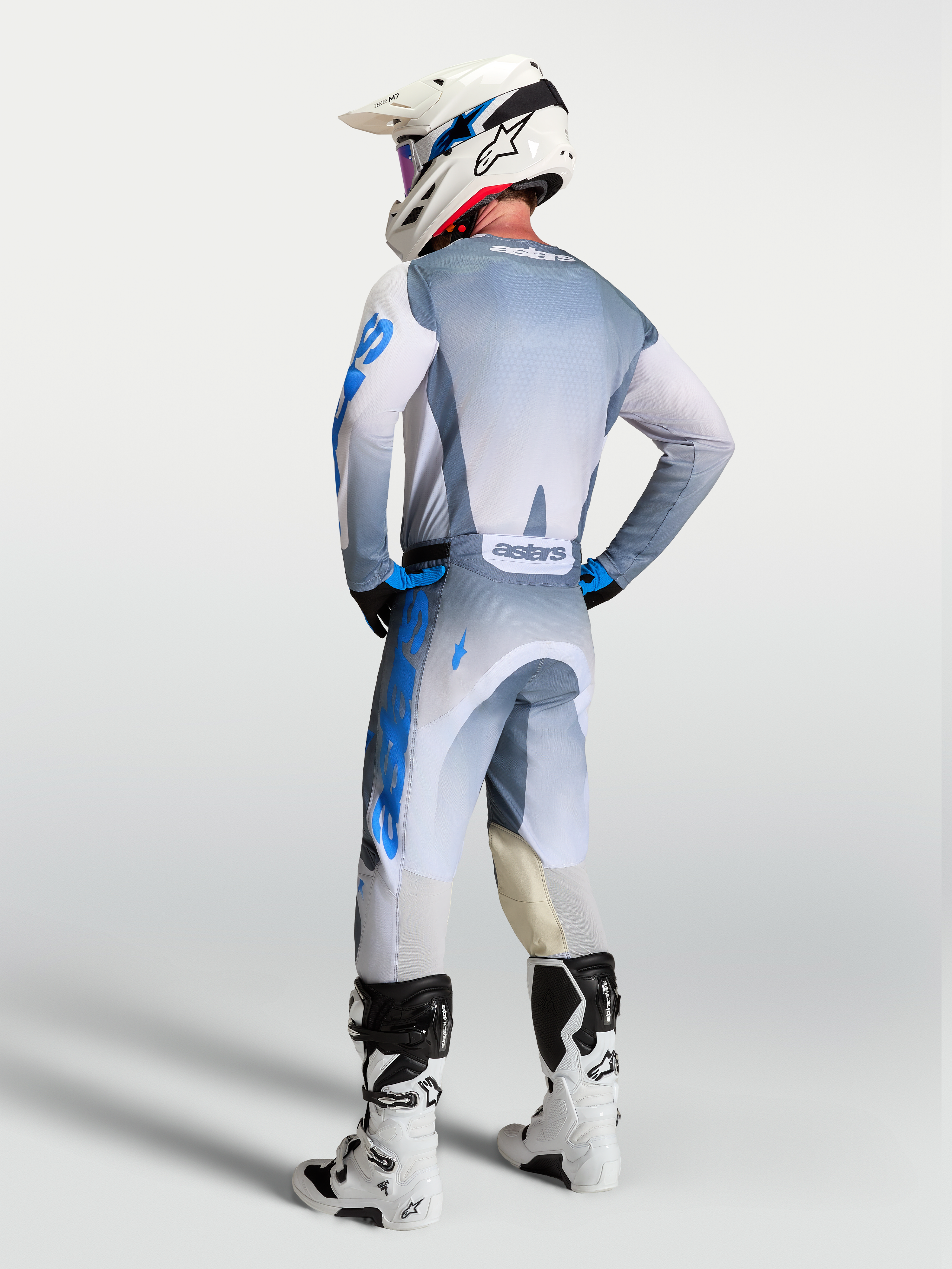 Alpinestars calças e gear set Racer Amber 2027, equipamento de motocross cinzento e azul, vista traseira num piloto.