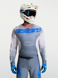 Alpinestars Camisola Racer Amber, camisola de motocross para homem, cinzenta e azul, com capacete de MX branco e óculos