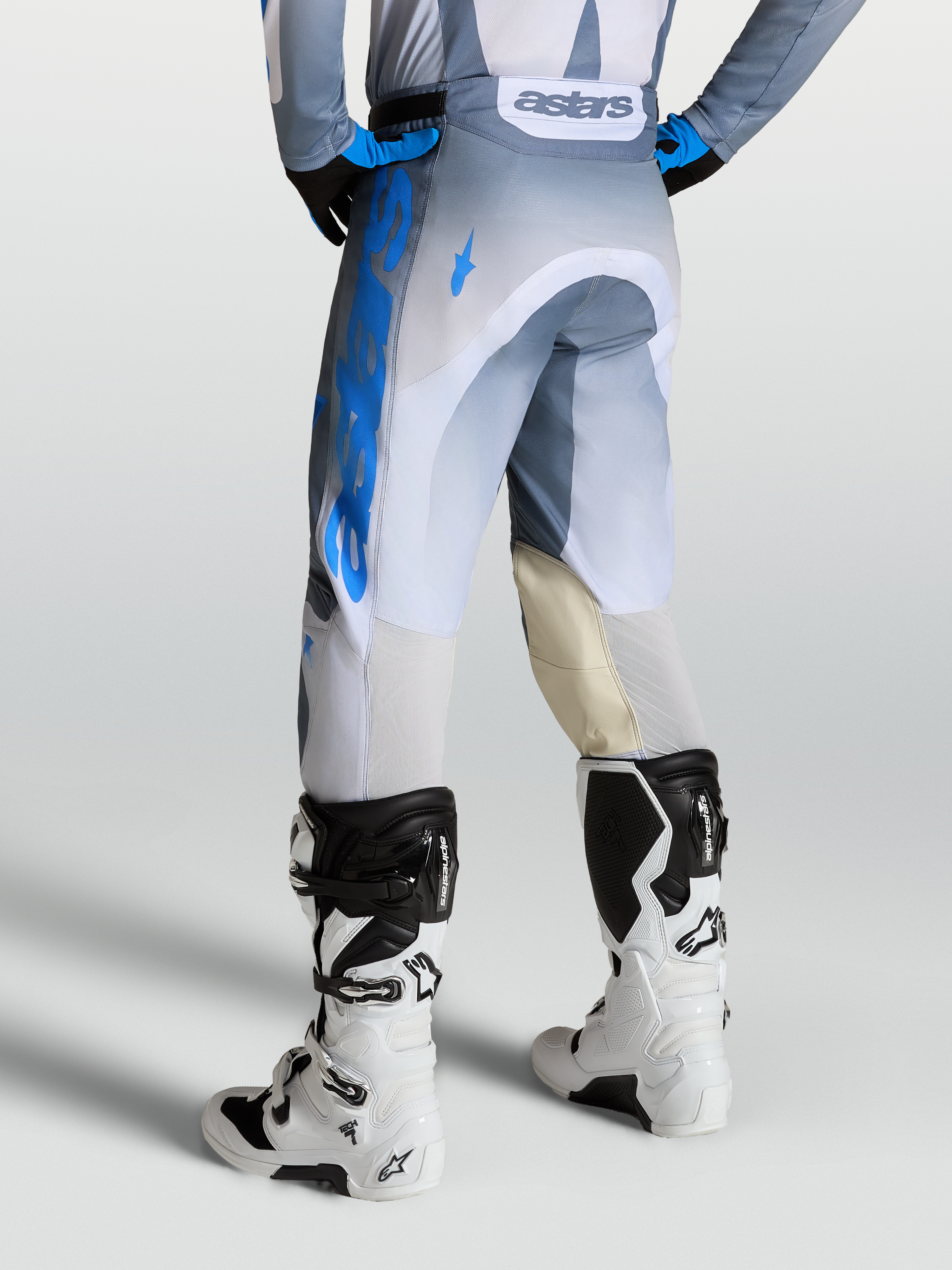 Alpinestars Calças Racer Amber, calças de motocross para homem, cinzento, azul e branco, vista traseira, painéis de pele nos joelhos e ventilação traseira